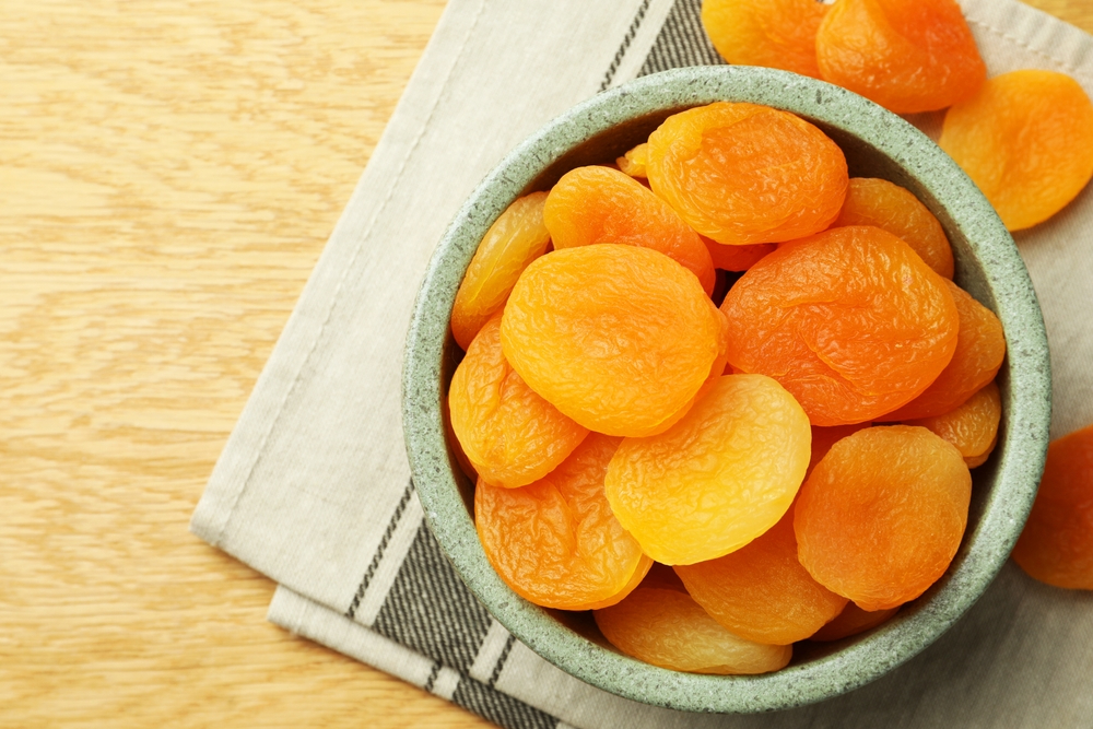 Bowl of tasty apricots on wooden table