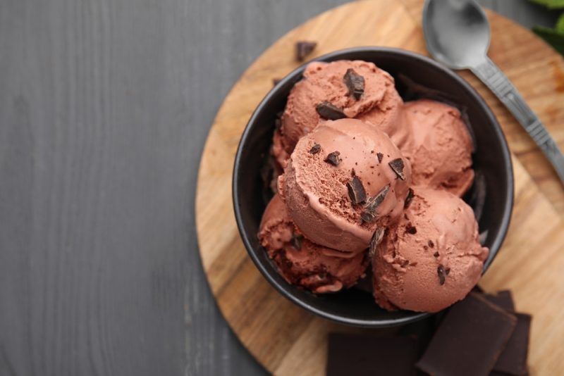 Bowl with tasty chocolate ice cream on wooden board