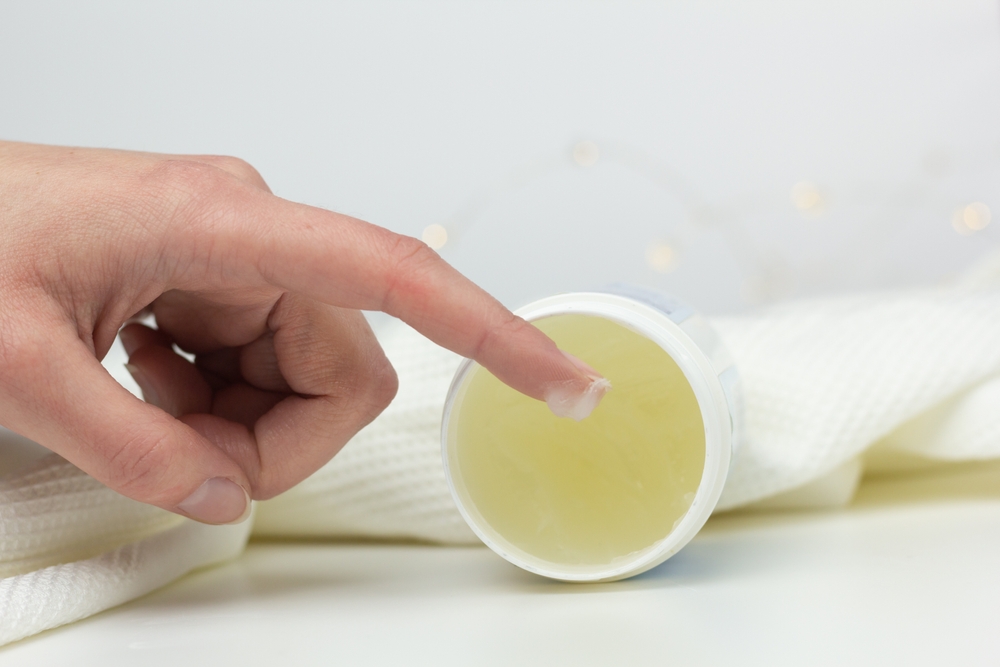 Closeup of a person applying petroleum jelly to their hand