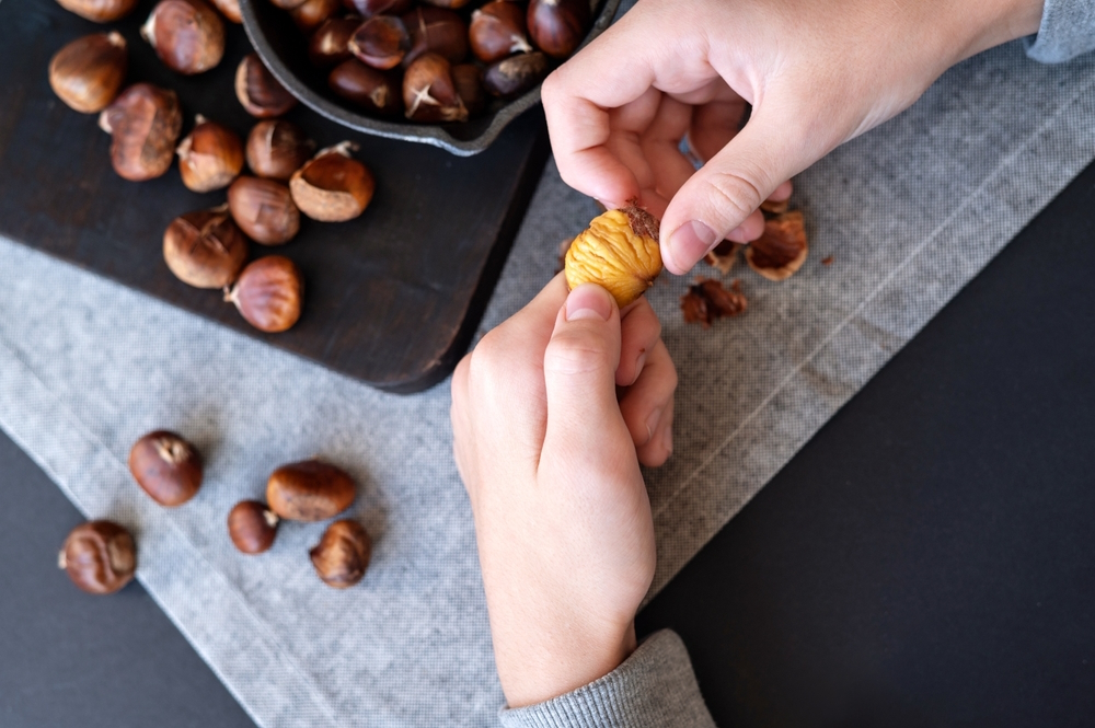 Hands-peeling-chestnuts-from-shell