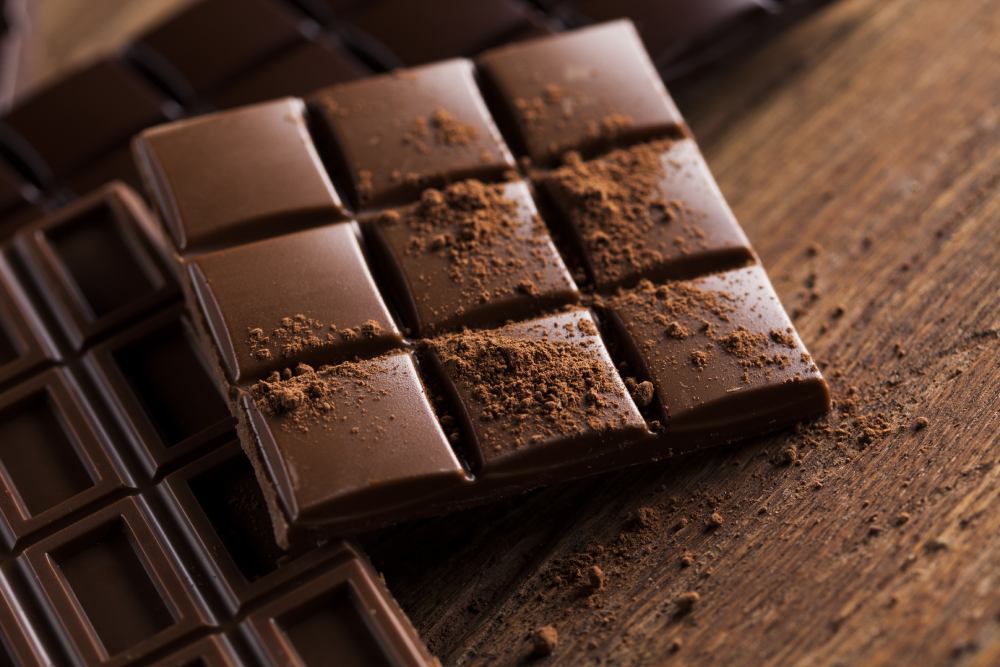 Milk and dark chocolate bar powder on a wooden table