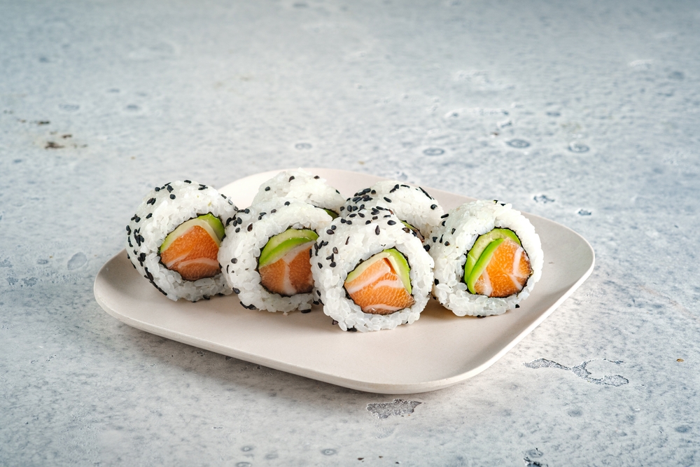 set of fresh sushi rolls with salmon, avocado and black sesame seeds served on a plate