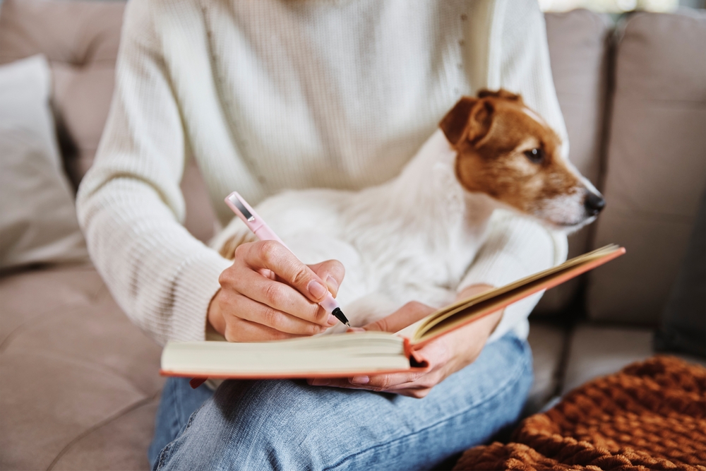 woman writing at home with her dog